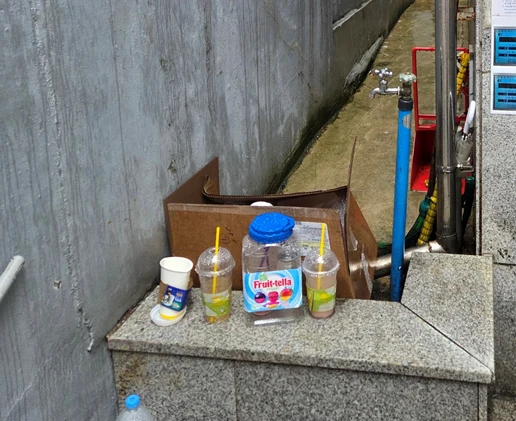 펜스 설치 전 자투리 공간에 쓰레기가 투기된 현장 — 커피컵과 페트병이 쌓여 있고 외부인 출입 흔적이 있다
